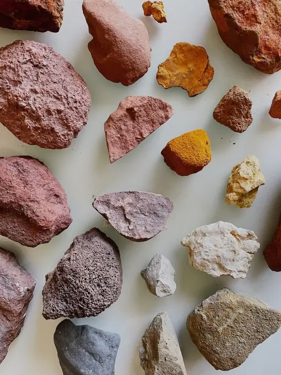 Piedras de tonos ocre, rojizo y gris sobre fondo claro — Hilando Culturas